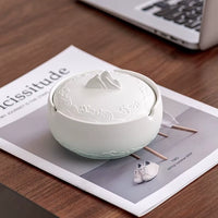 Cendrier décoratif en céramique avec couvercle blanc sur une table